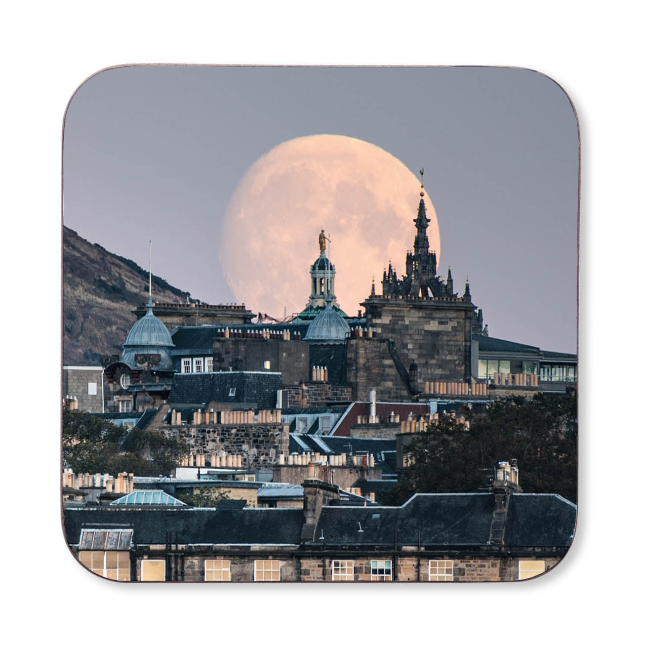 Full moon over a cityscape with prominent buildings on a coaster. 
