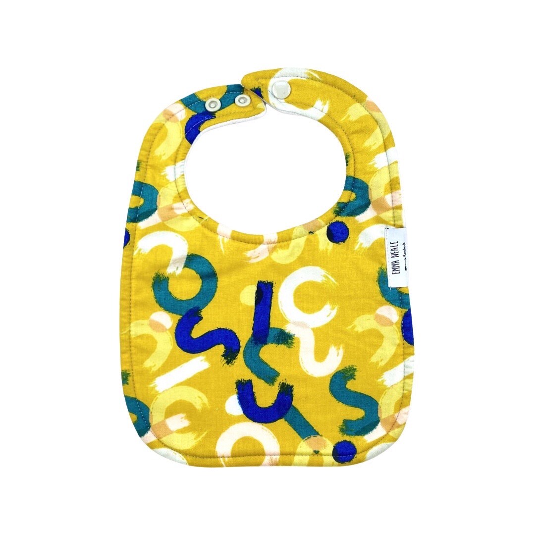 Traditional style bib in 'mustard brush strokes' fabric with adjustable neck fasteners.