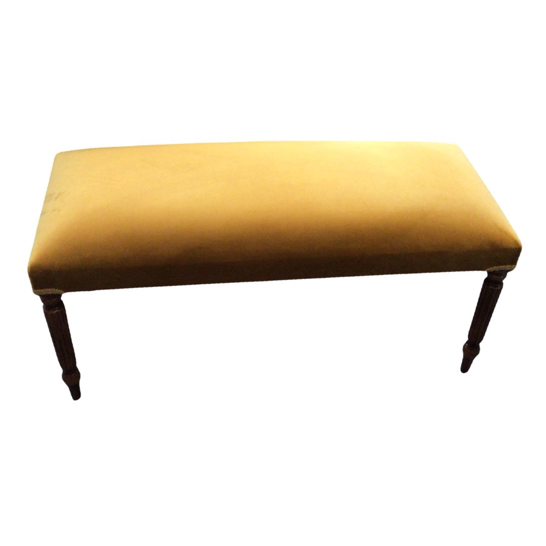 A rectangular velvet bench with mahogany stained legs in a mustard colour design.