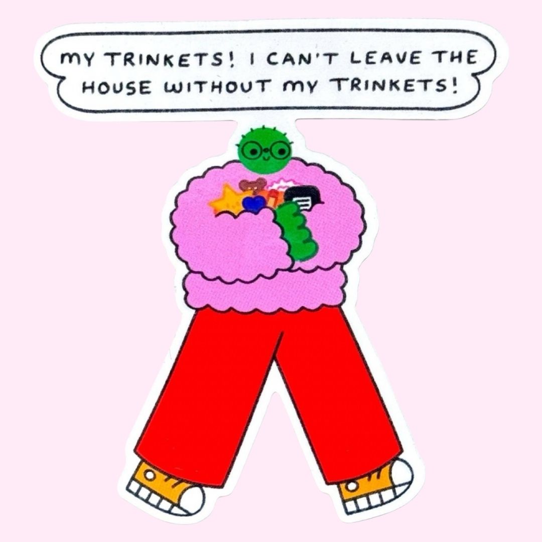 A sticker featuring a cartoon character with a pink fuzzy jumper, red pants, yellow shoes, and a green head, with a speech bubble above reading 'MY TRINKETS! I CAN'T LEAVE THE HOUSE WITHOUT MY TRINKETS!', on a pink background.