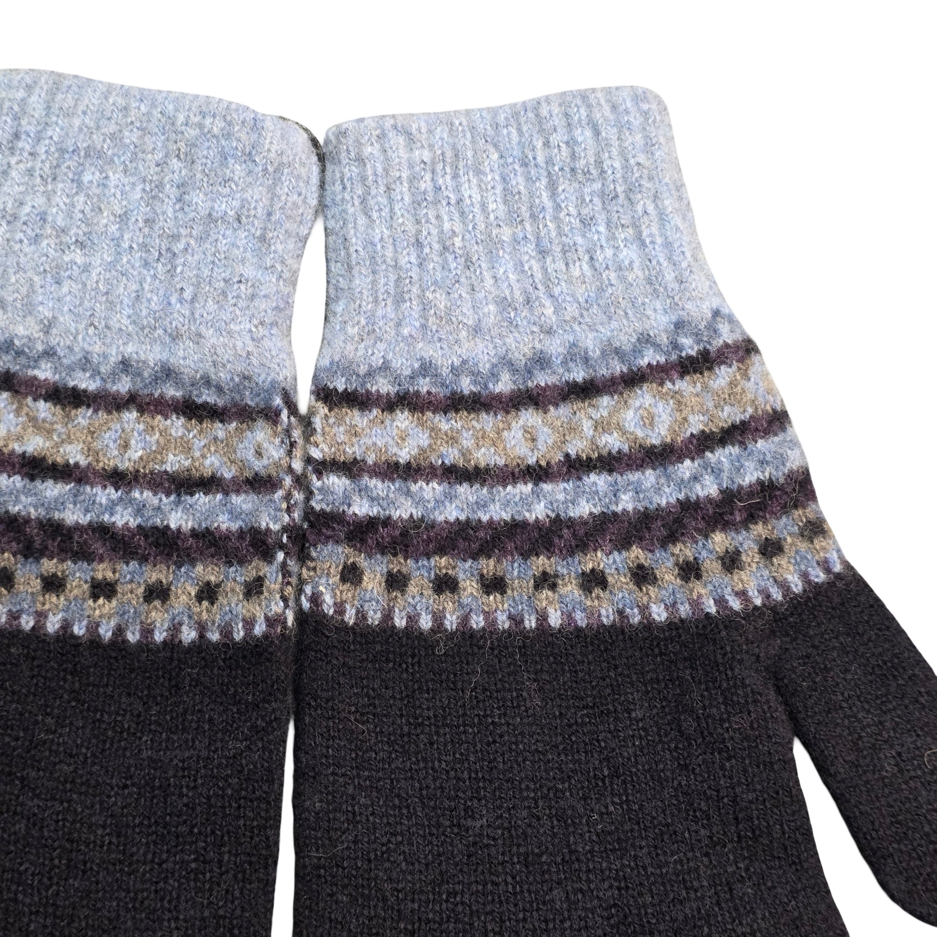 Close-up of black gloves with patterned cuffs on a white background.