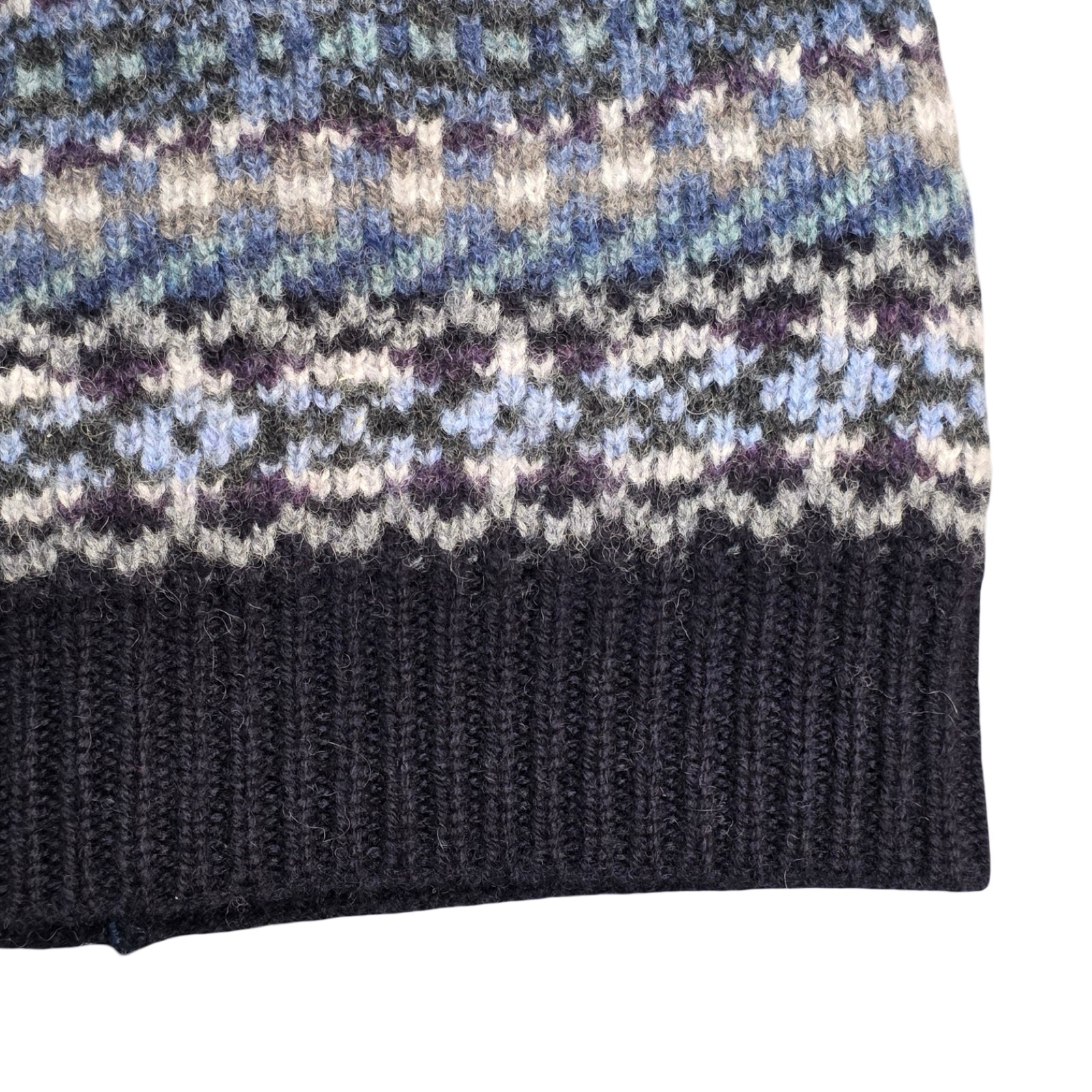 Close-up of a knitted fabric with a patterned top and plain bottom section.