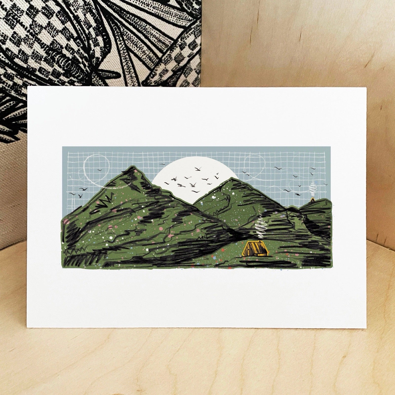 Greeting card with mountain design on a wooden surface.