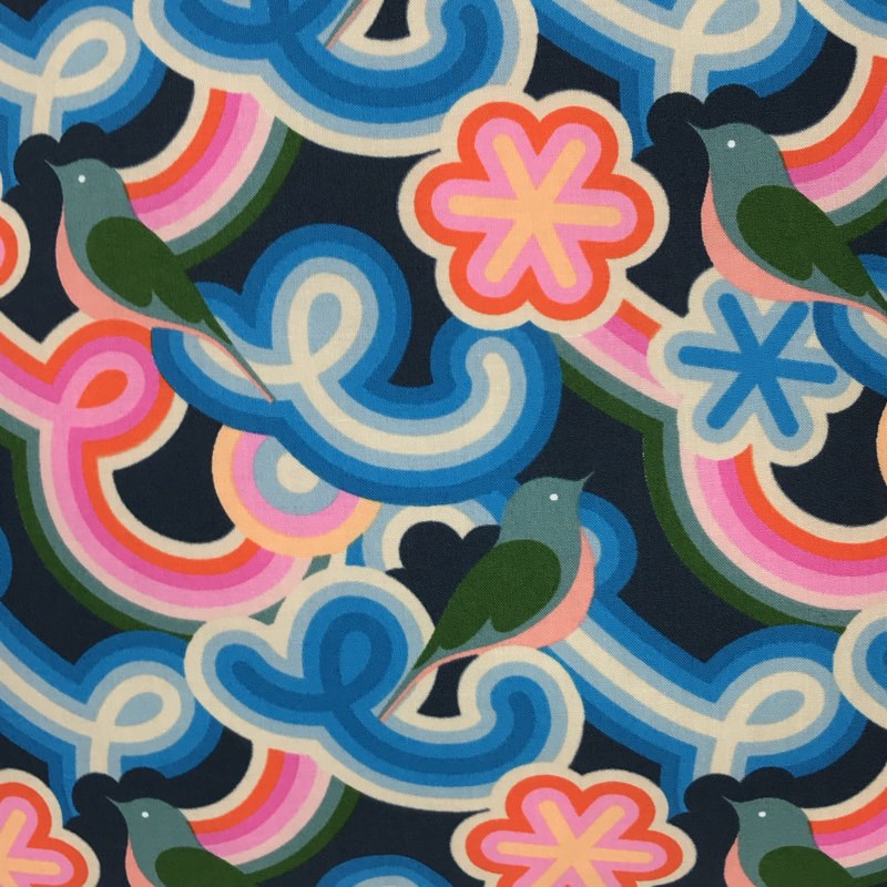 A cushion cover with a geometric pattern featuring navy background and vibrant swirly shapes in pink, blue, and red, along with green birds.