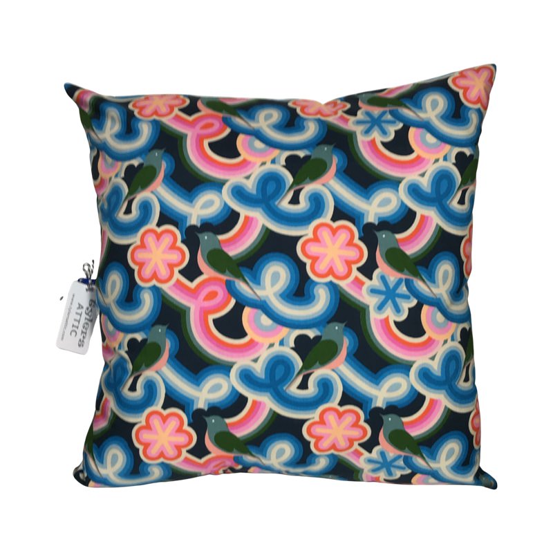 A cushion cover with a geometric pattern featuring navy background and vibrant swirly shapes in pink, blue, and red, along with green birds.
