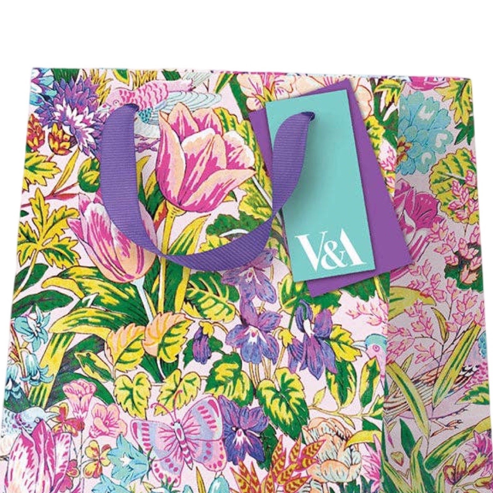 A V&A branded gift bag featuring a vibrant, multicolour botanical and butterfly pattern with purple ribbon handles and a matching purple V&A tag.