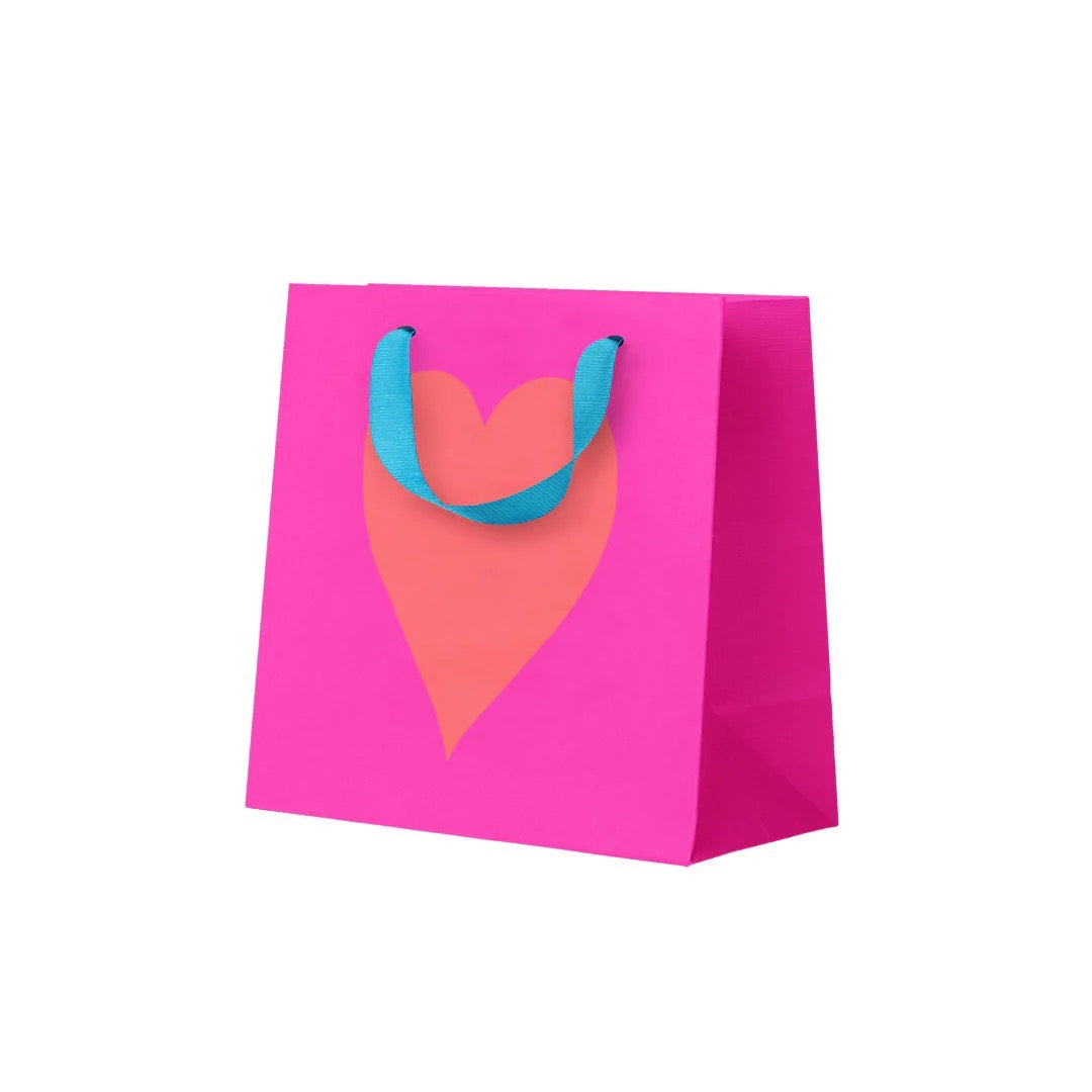 Pink gift bag with a heart design and blue handles on a white background.