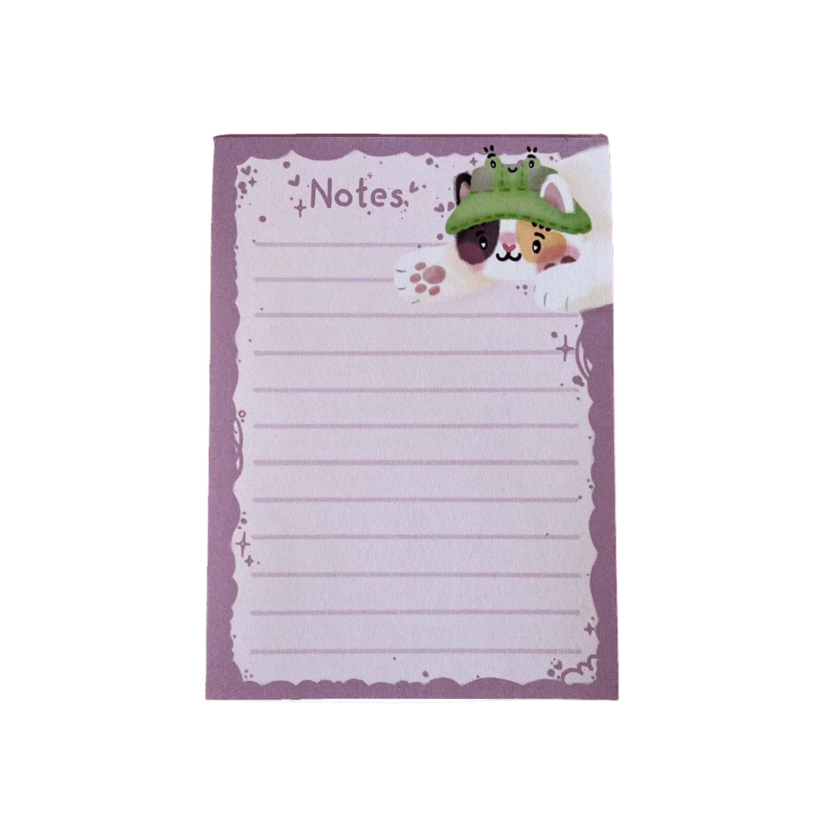 A 50-page pink tear-off lined notepad with Bucket the calico cat, wearing their frog bucket hat. Bucket is trying to catch your pen as you write your notes!