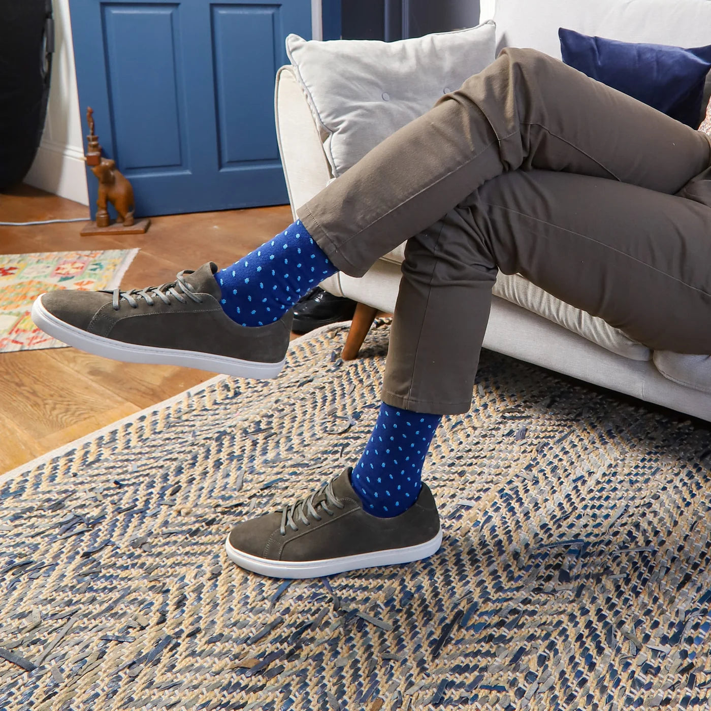 Person wearing blue socks sat on a sofa in a blue and beige room.