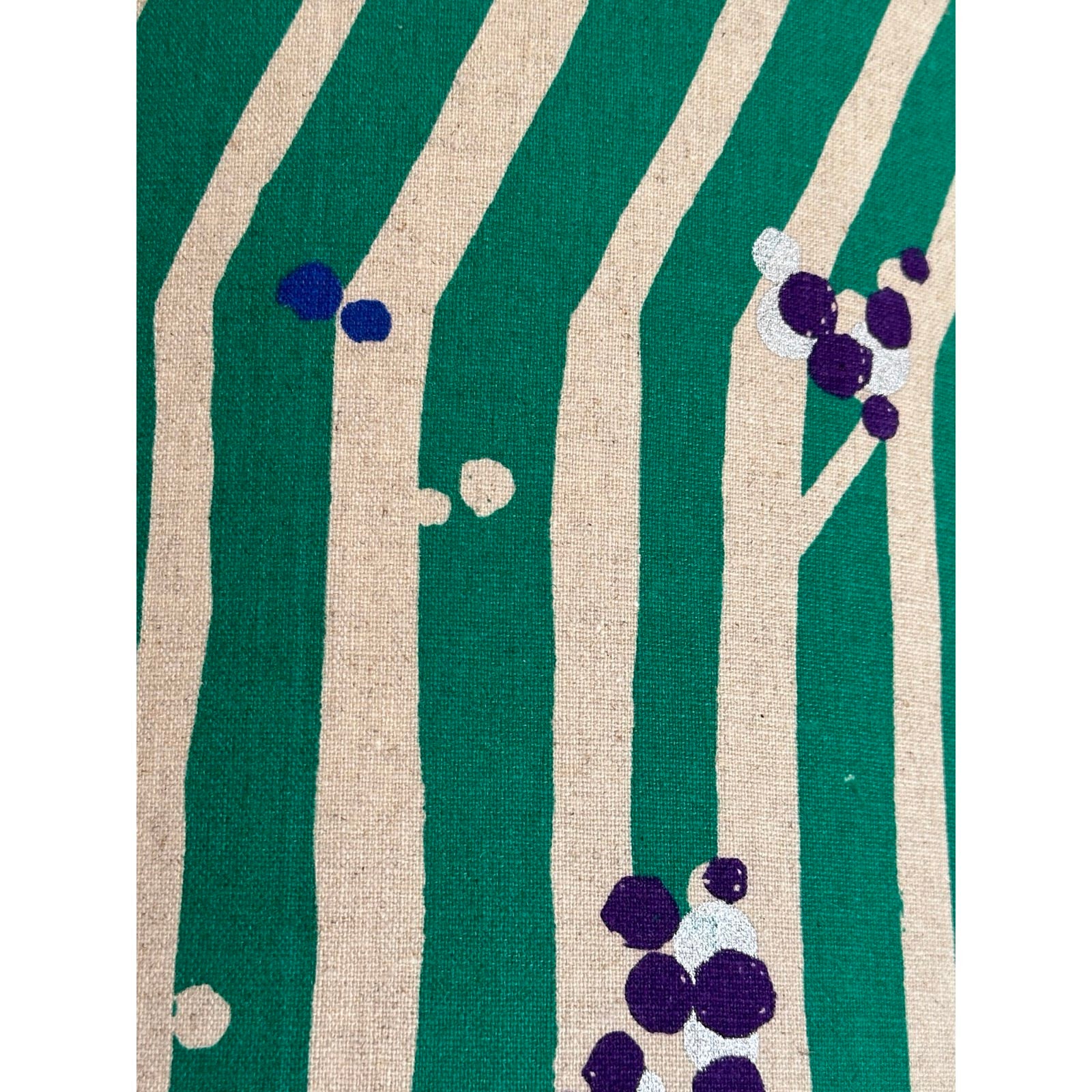 A cushion cover with green and white stripes, featuring white branches with clusters of purple nuts.