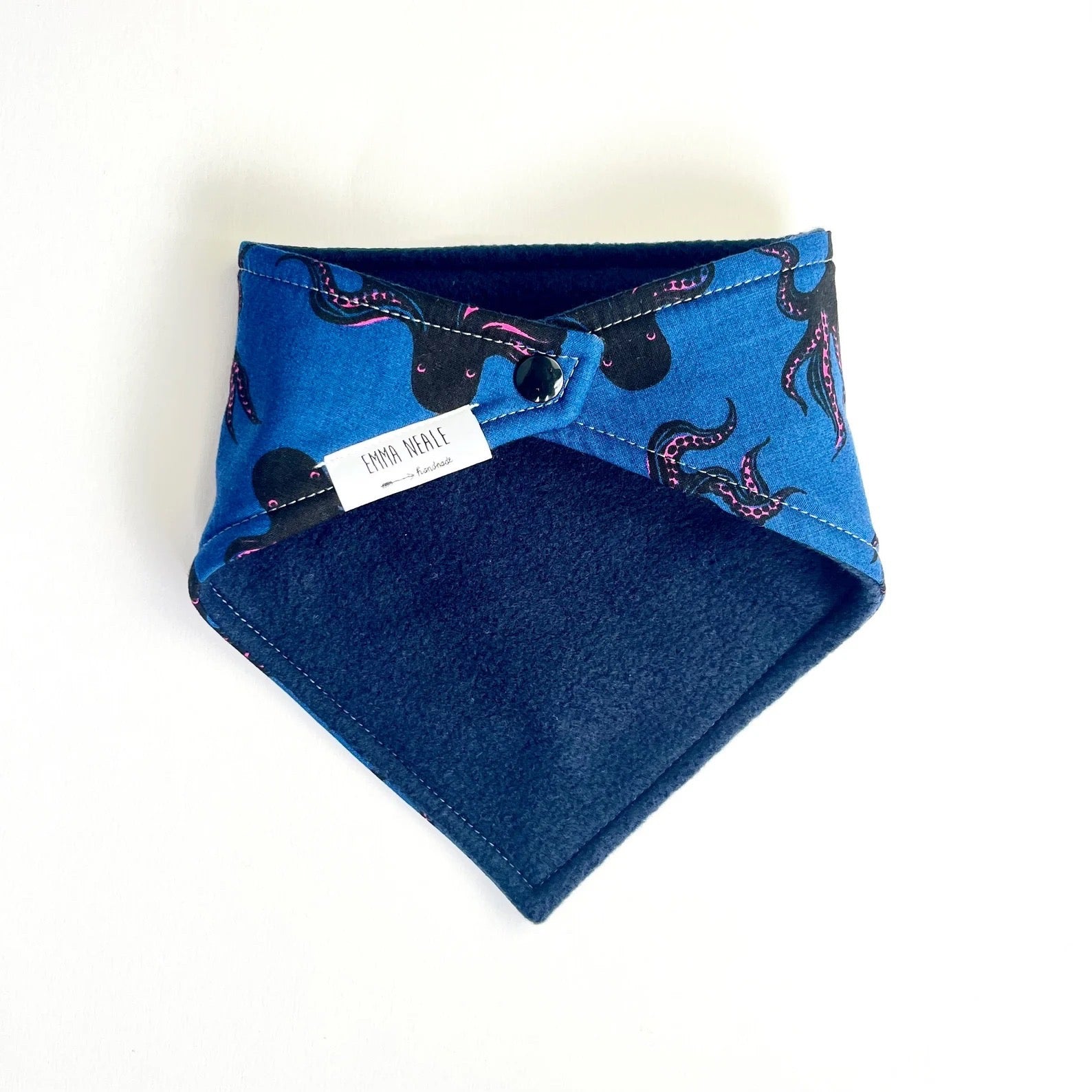 Back of bandana bib for babies with an octopus pattern on a blue background with a white label.