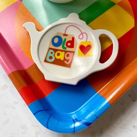 Colourful melamine tea bag holder in the shape of a teapot with an illustration of a tea bag on a white background and the text 'Old Bag'. 