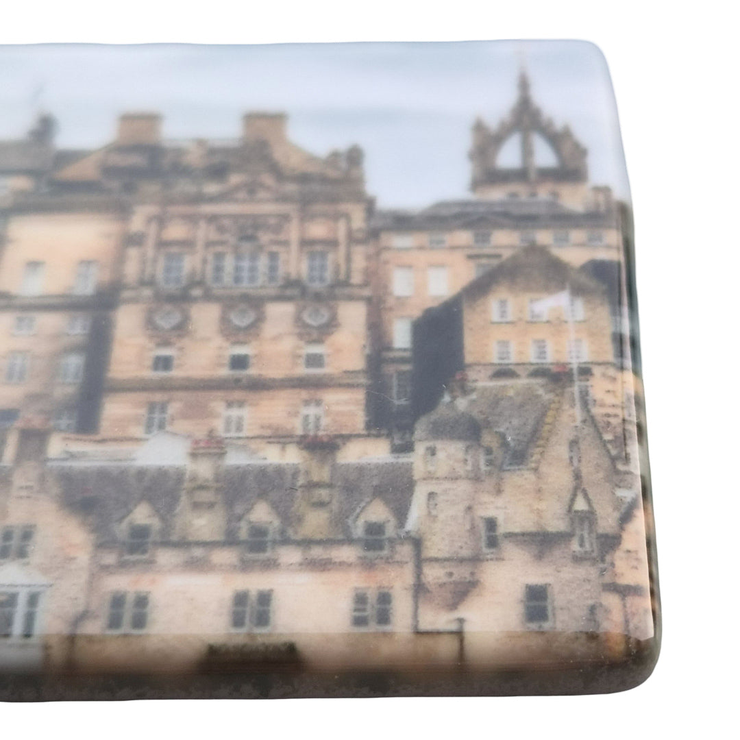 A close up of a ceramic tile magnet. 