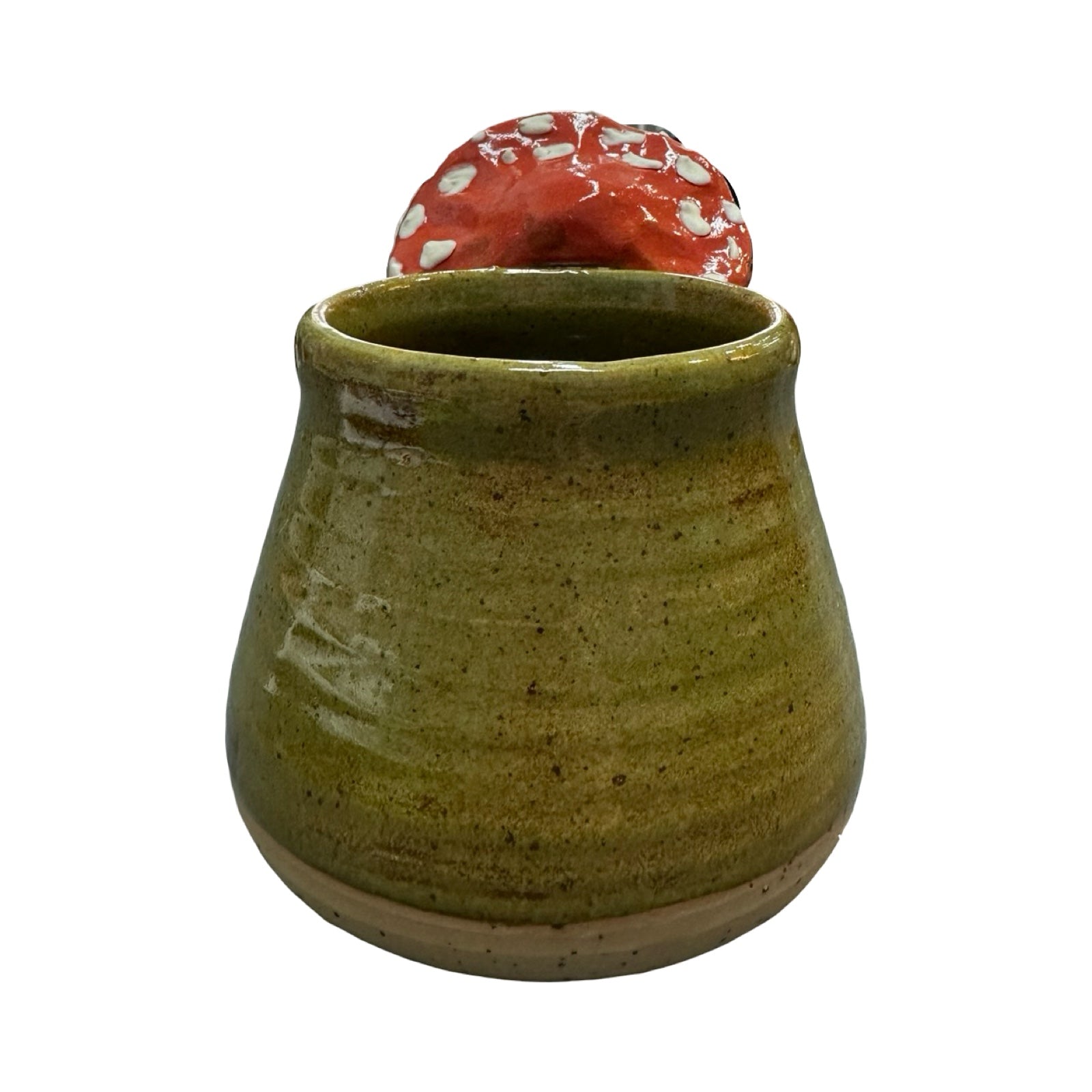 Green ceramic mug with a red and white mushroom-shaped handle against a white background.