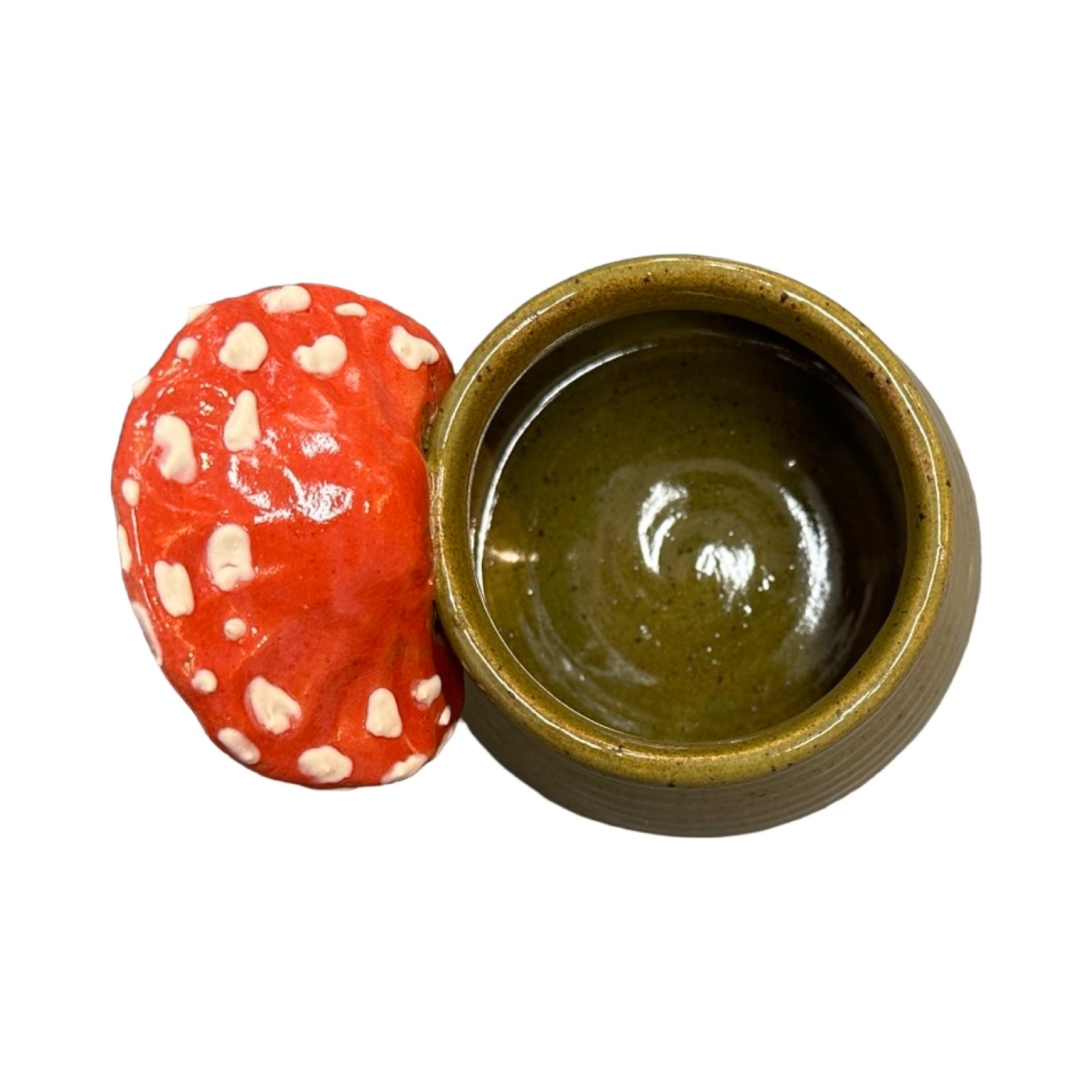 Ceramic mug with a red and white mushroom handle on a white background.