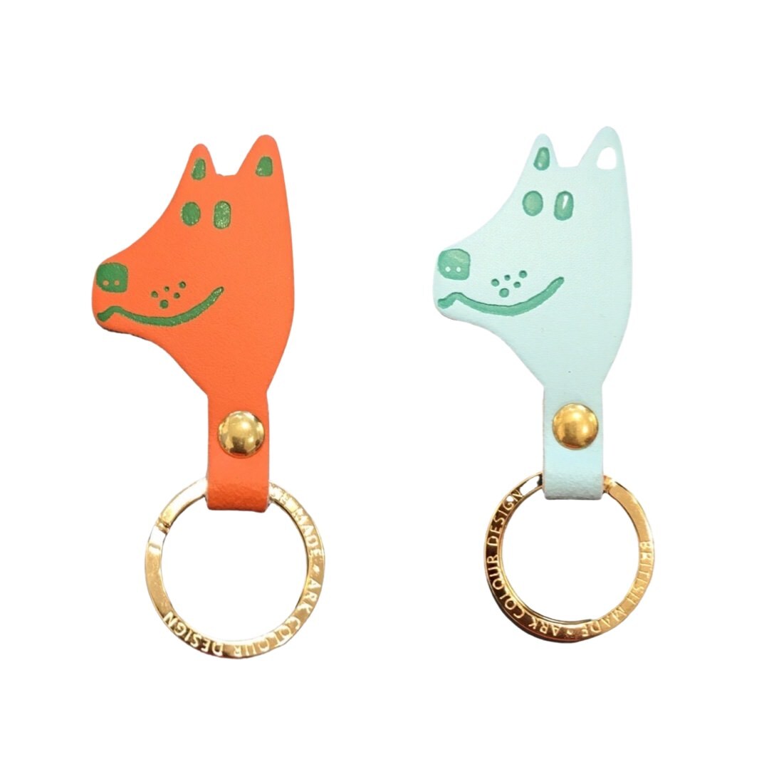 Orange and turquoise dog head shaped keyrings with green facial details and a gold ring.