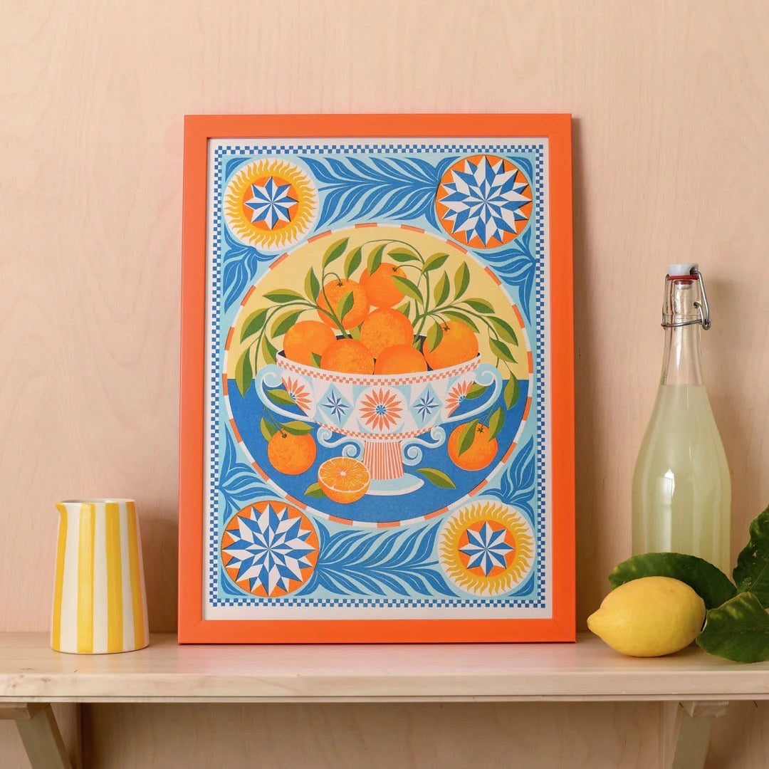 Decorative print with orange design on a shelf with a bottle and lemon.
