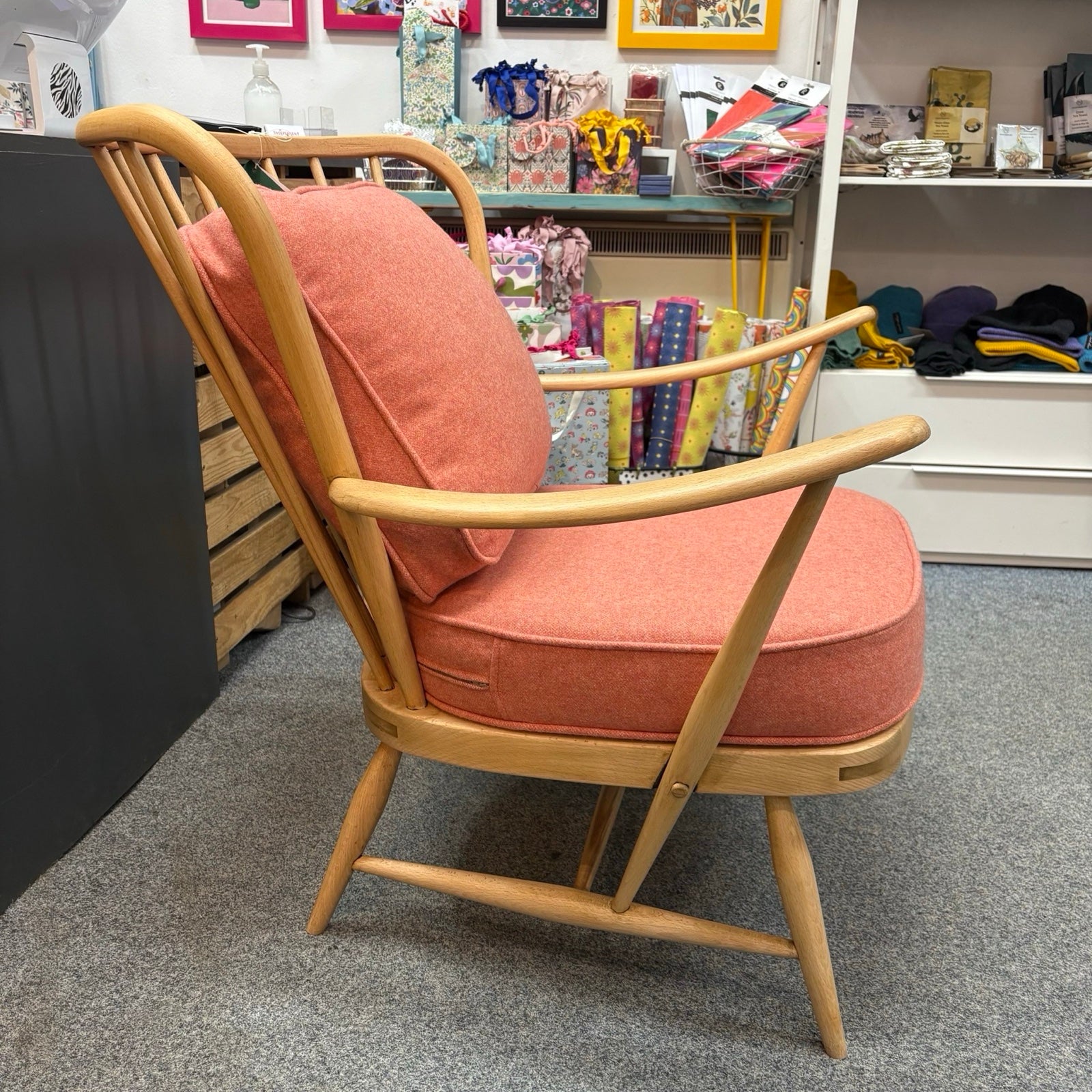 Wooden armchair with orange cushion in a store setting.