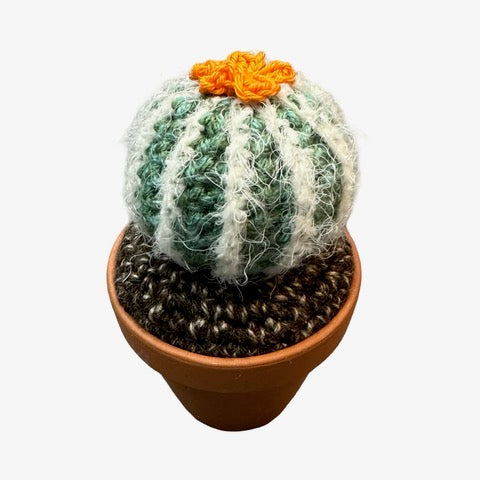 Handmade round crochet cactus with an orange flower in a terracotta pot. 