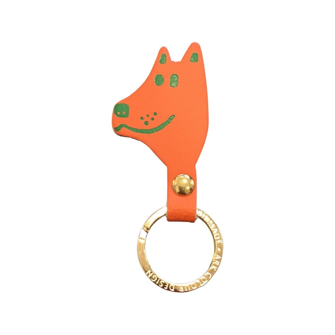 An orange dog head shaped keyring with green facial details and a gold ring.