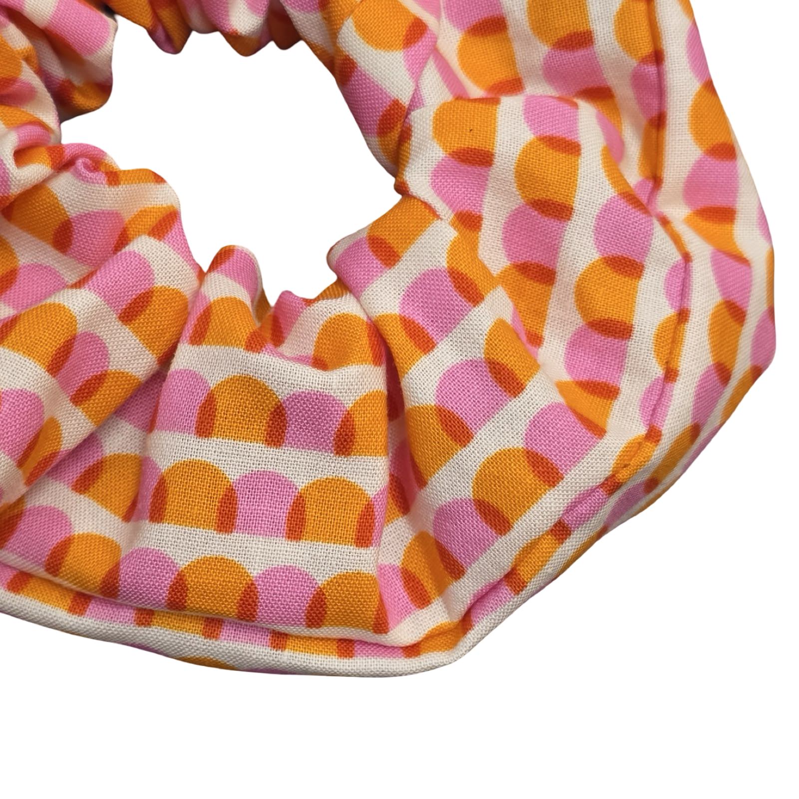 This handmade hair scrunchie is made from 100% cotton fabric with an orange and pink scalloped pattern.