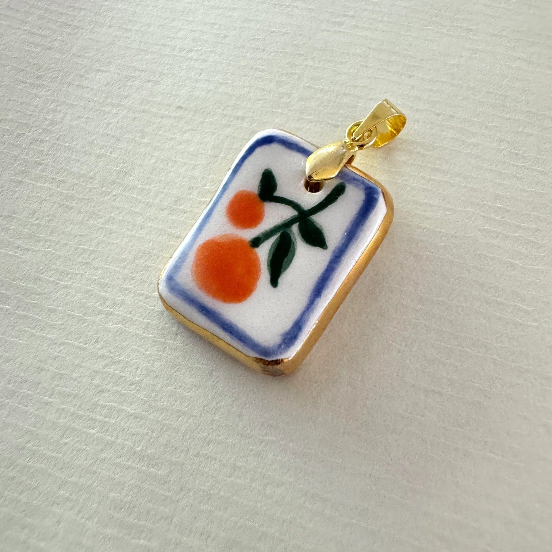 Small rectangular pendant with orange design on a light grey background.
