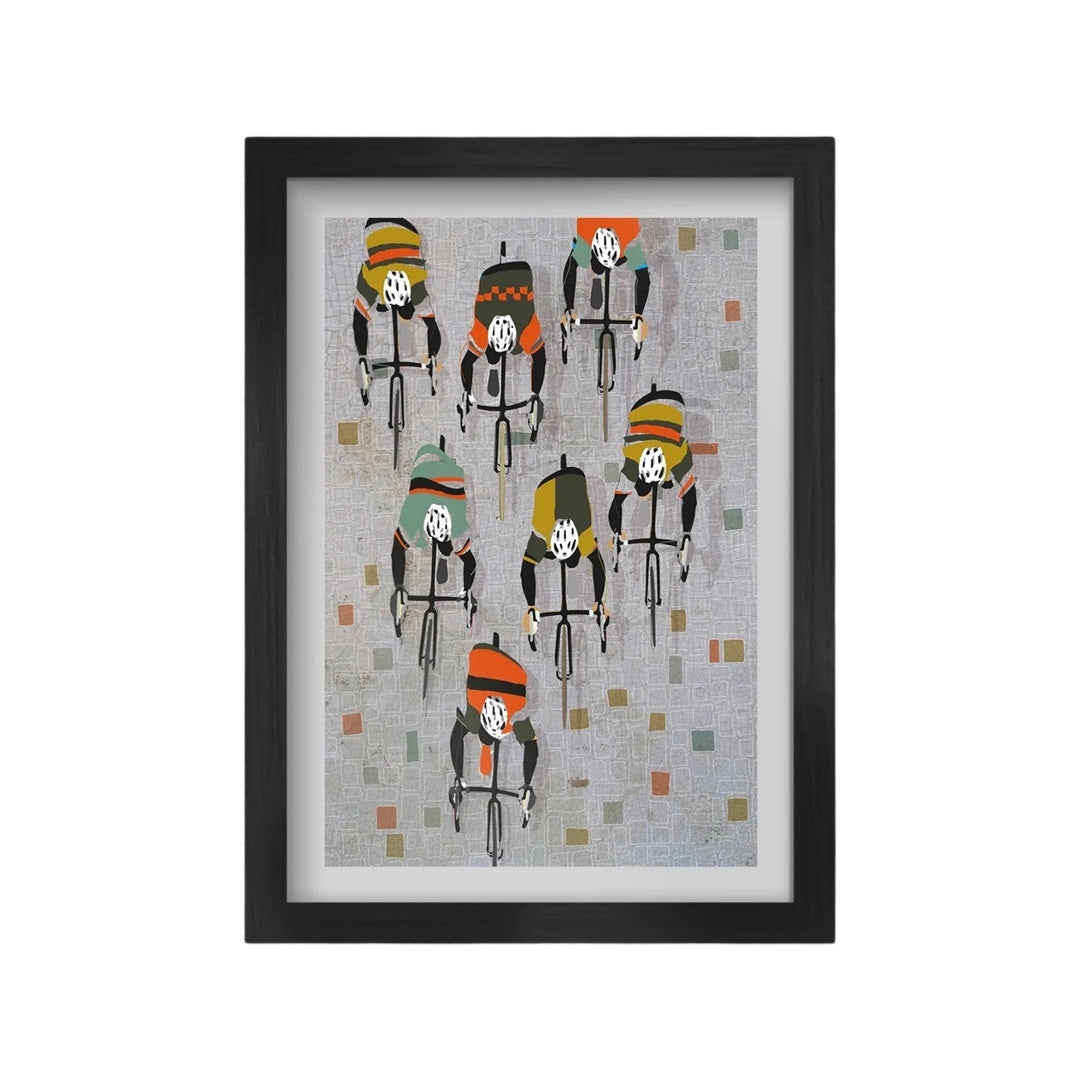 A framed A3 cycling print featuring seven silhouetted cyclists in different team colours riding over cobblestones, with a black frame.
