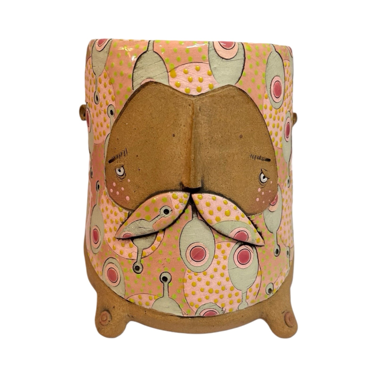 A ceramic beaker with a male moustached face and a cream and red paddle pattern on a pink background.