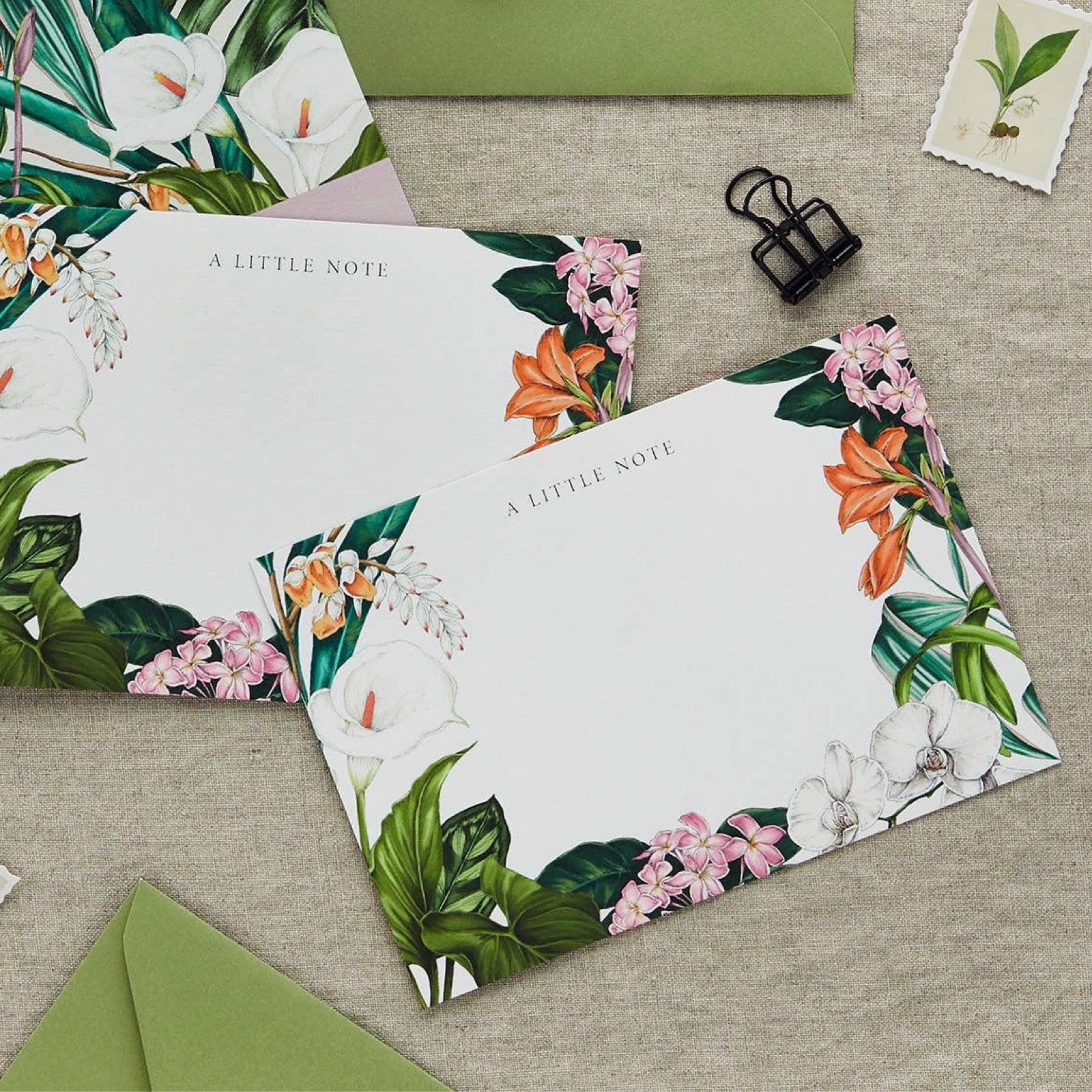 Floral stationery set with 'A Little Note' on a textured surface with green envelopes.