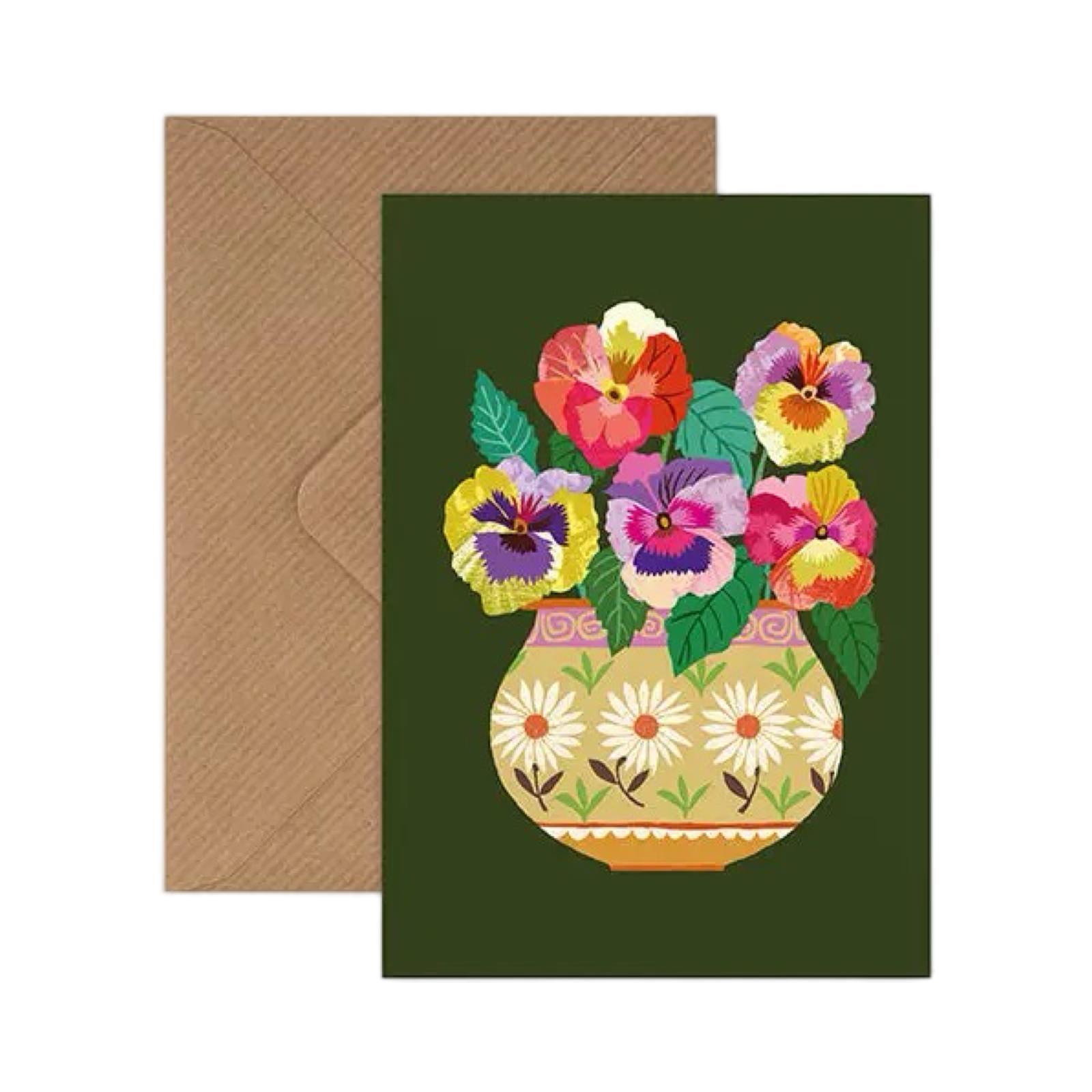 Card featuring a bunch of colourful pansies in a brown and pink floral vase, all on a dark green background.