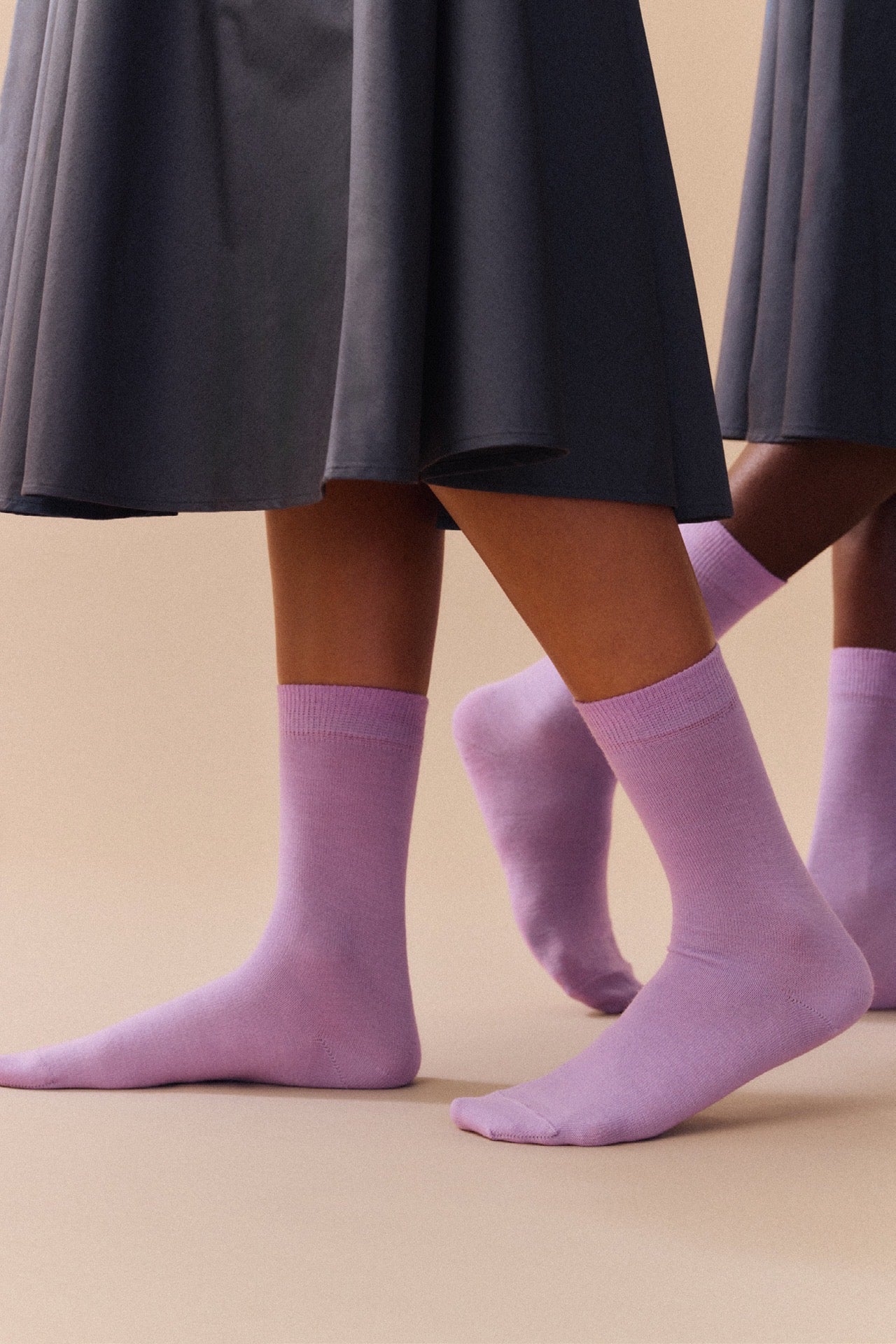 Parma violet socks worn with a dark skirt on a beige background.