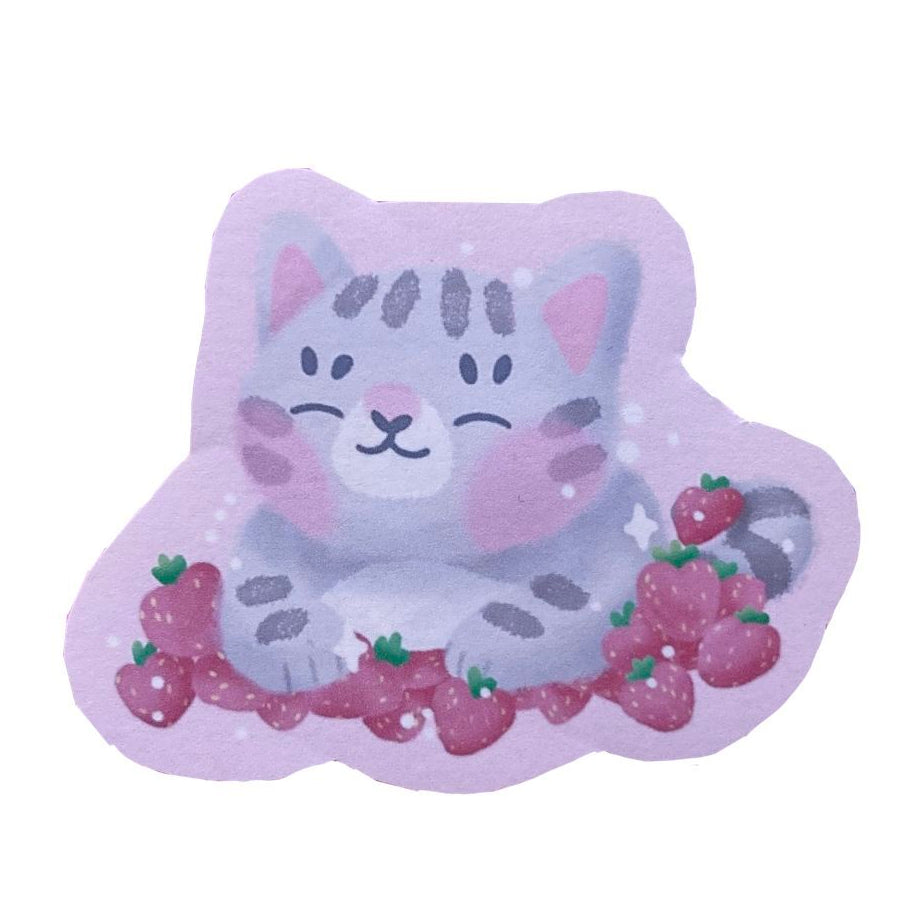 Handmade sticker of a grey tabby cat, smiling while they lie in a bed of pawberries.