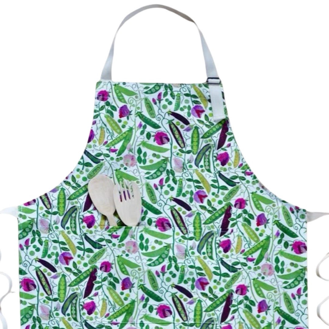 Apron featuring green, yellow and purple pods of peas with pink flowers and green foliage on a white background.