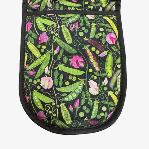 Oven gloves featuring green, yellow and purple pods of peas with pink flowers and green foliage on a black background.