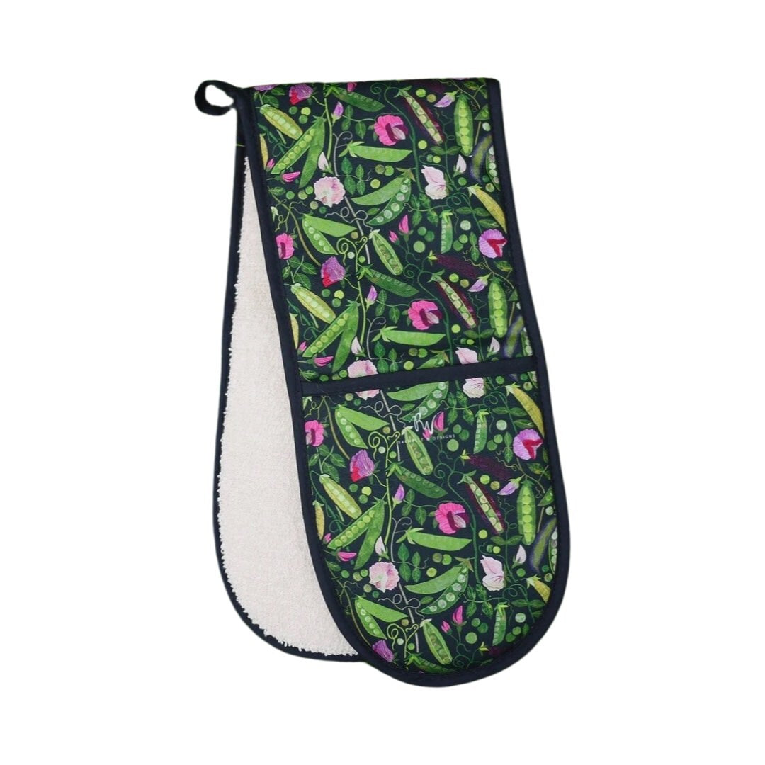Oven gloves featuring green, yellow and purple pods of peas with pink flowers and green foliage on a black background.
