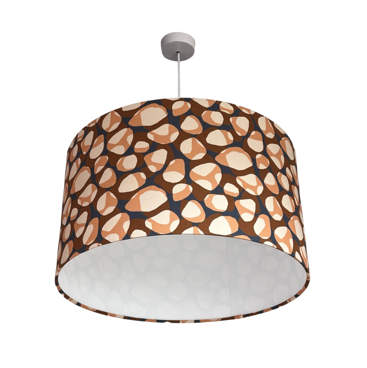 Drum lampshade covered in canvas fabric with brown, coral and cream pebbles on a navy background.