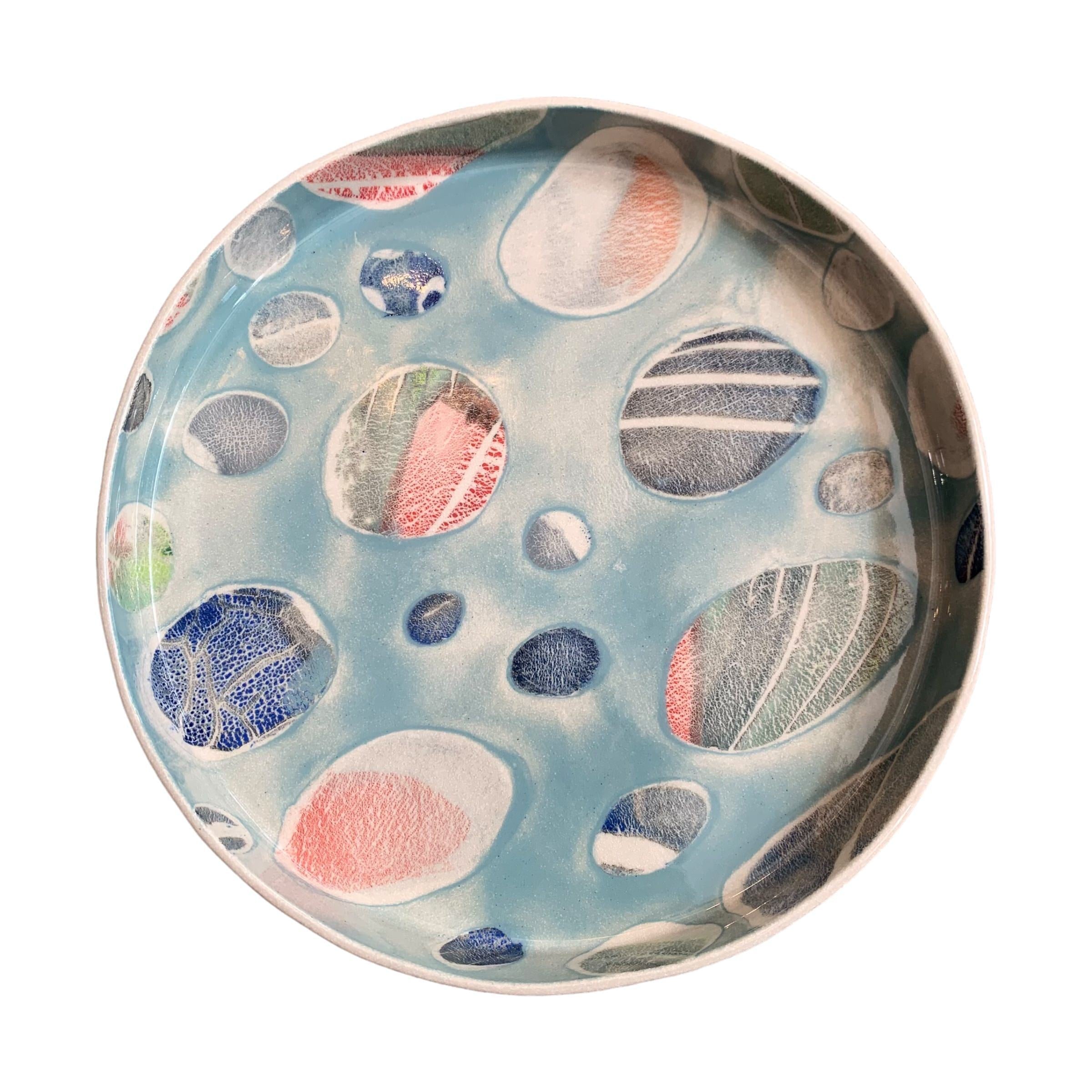A ceramic platter in blue with a colourful pebbles design.