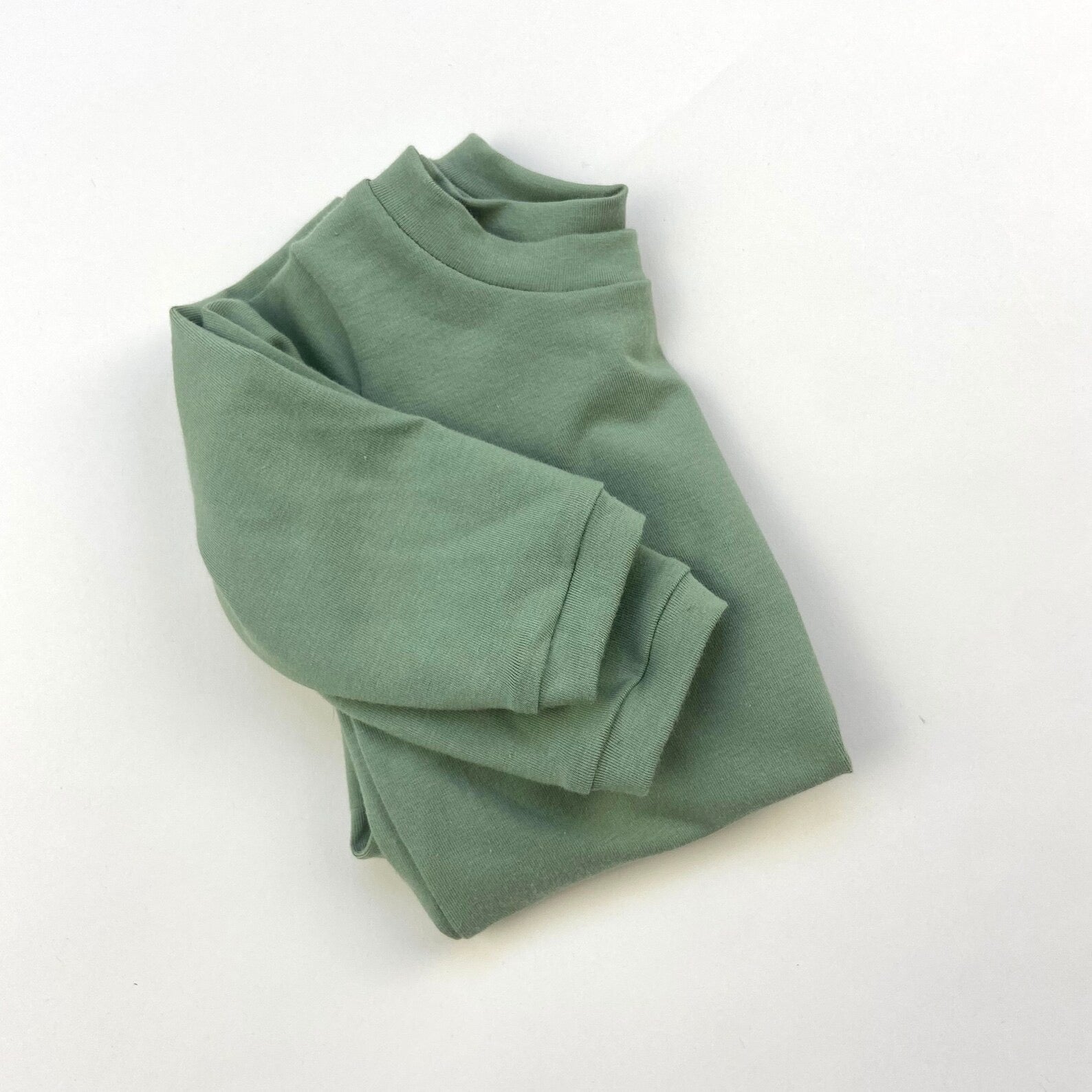 Folded green baby t-shirt on a white background.