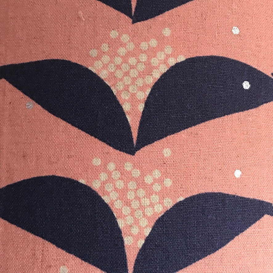 A cushion cover with a pink background and navy abstract floral pattern.