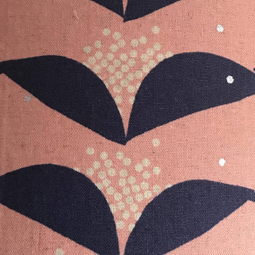 Fabric with a pink background and navy blue abstract floral pattern.