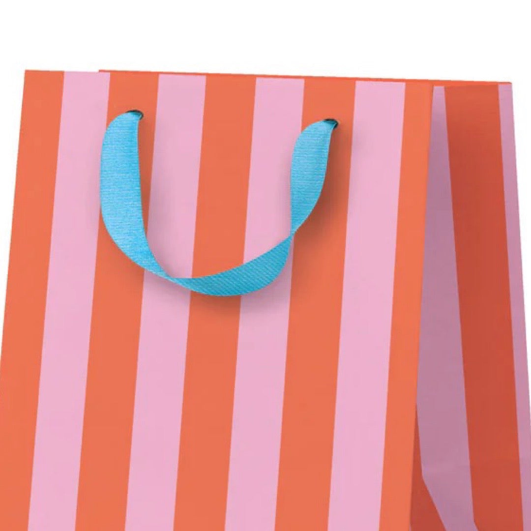 Striped gift bag with pink and orange vertical stripes and a blue handle on a white background.