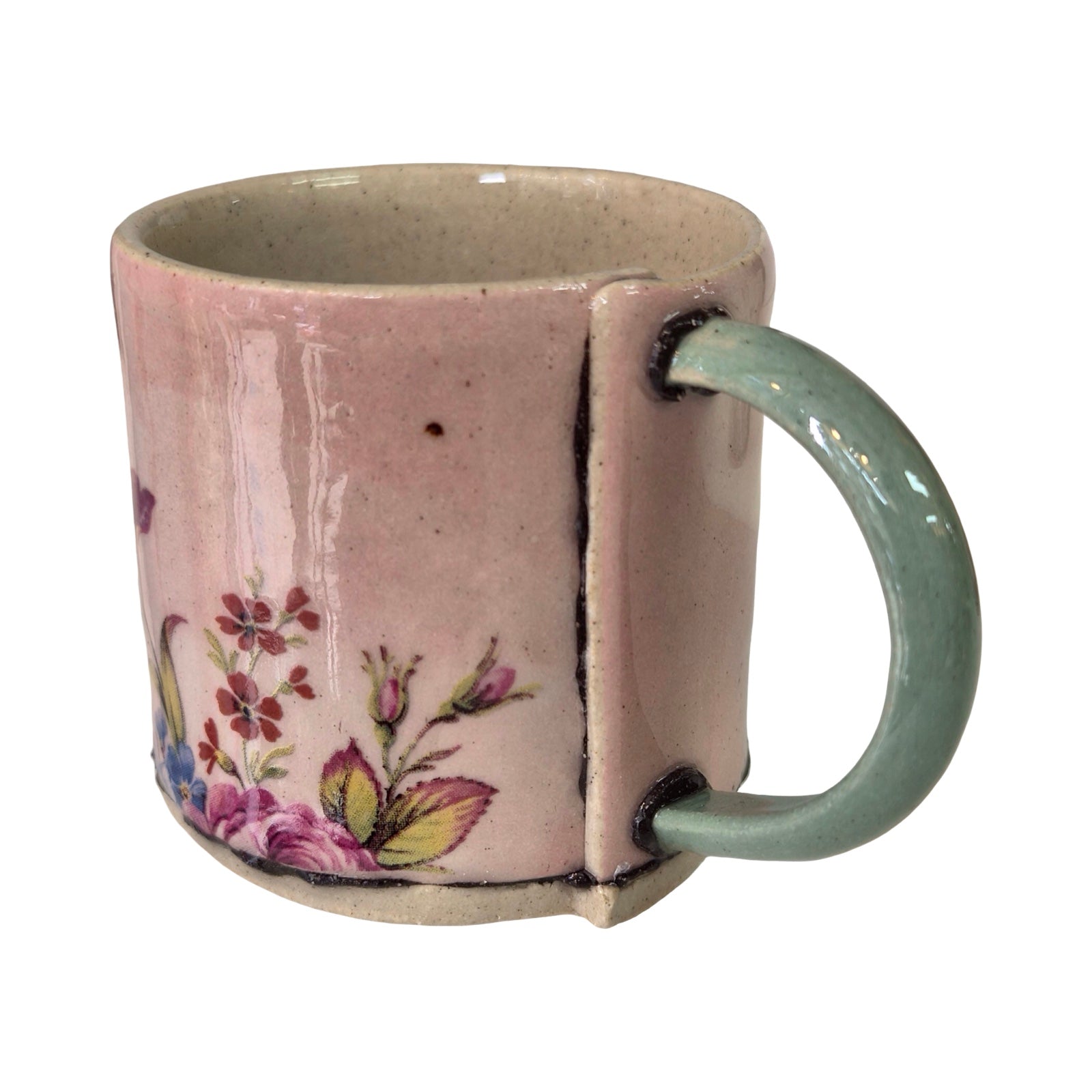 Ceramic mug with floral design and light green handle on a white background.