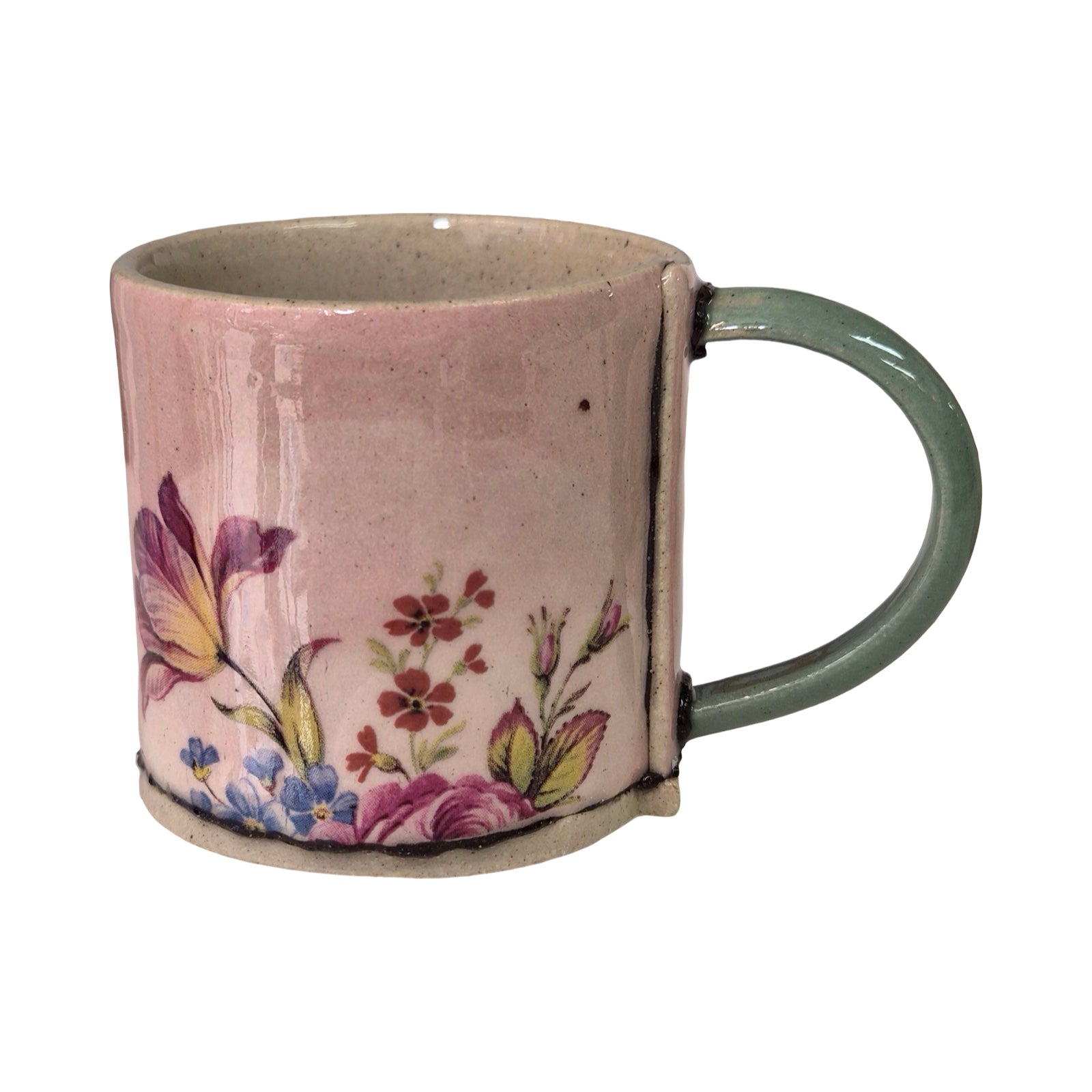 Pink mug with floral design and green handle on a white background.