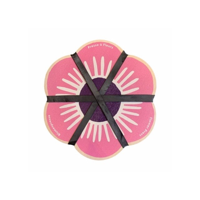 Floral-shaped flower press with pink and purple design, tied with black ribbon on a white background.