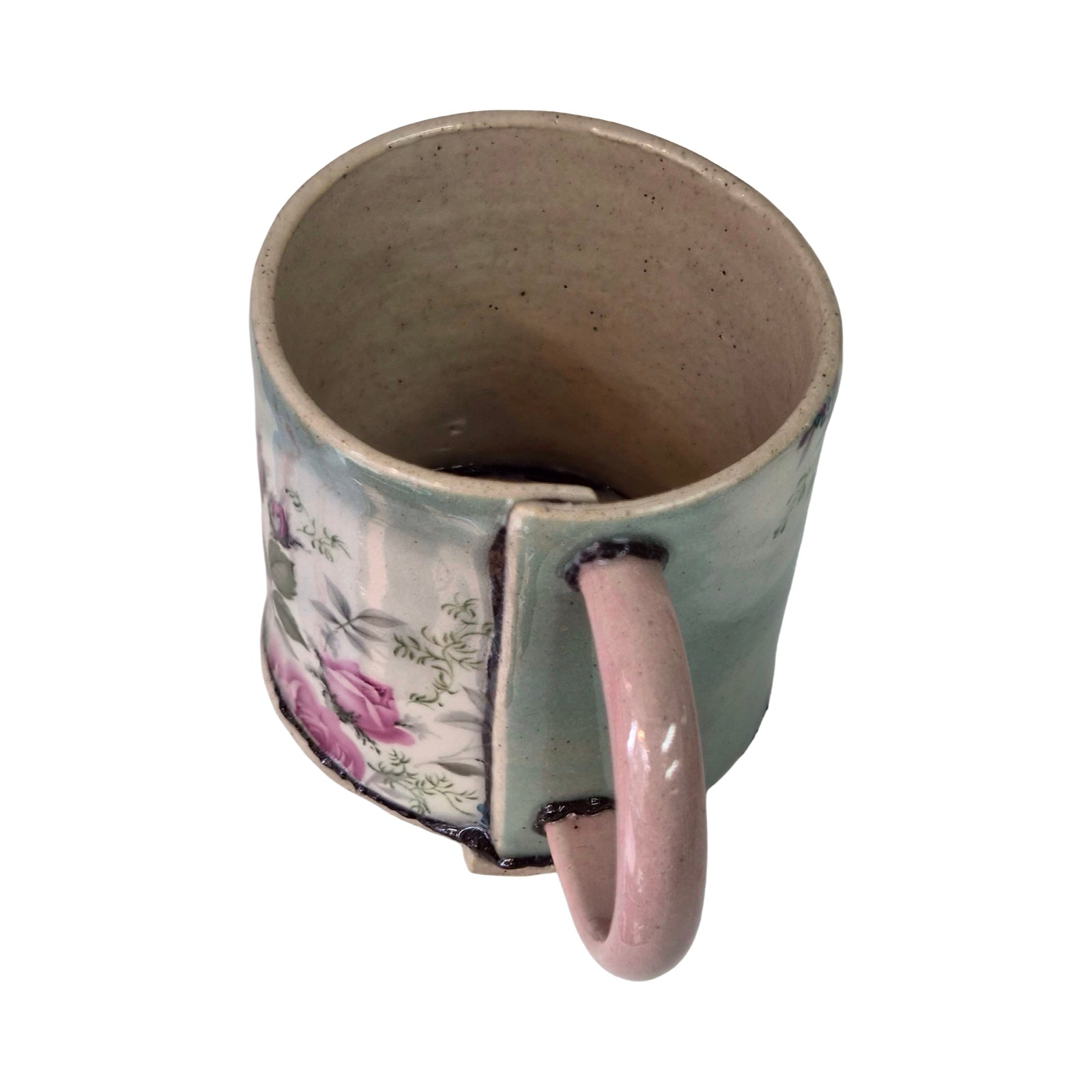 Ceramic mug with floral design and pink handle on a white background.
