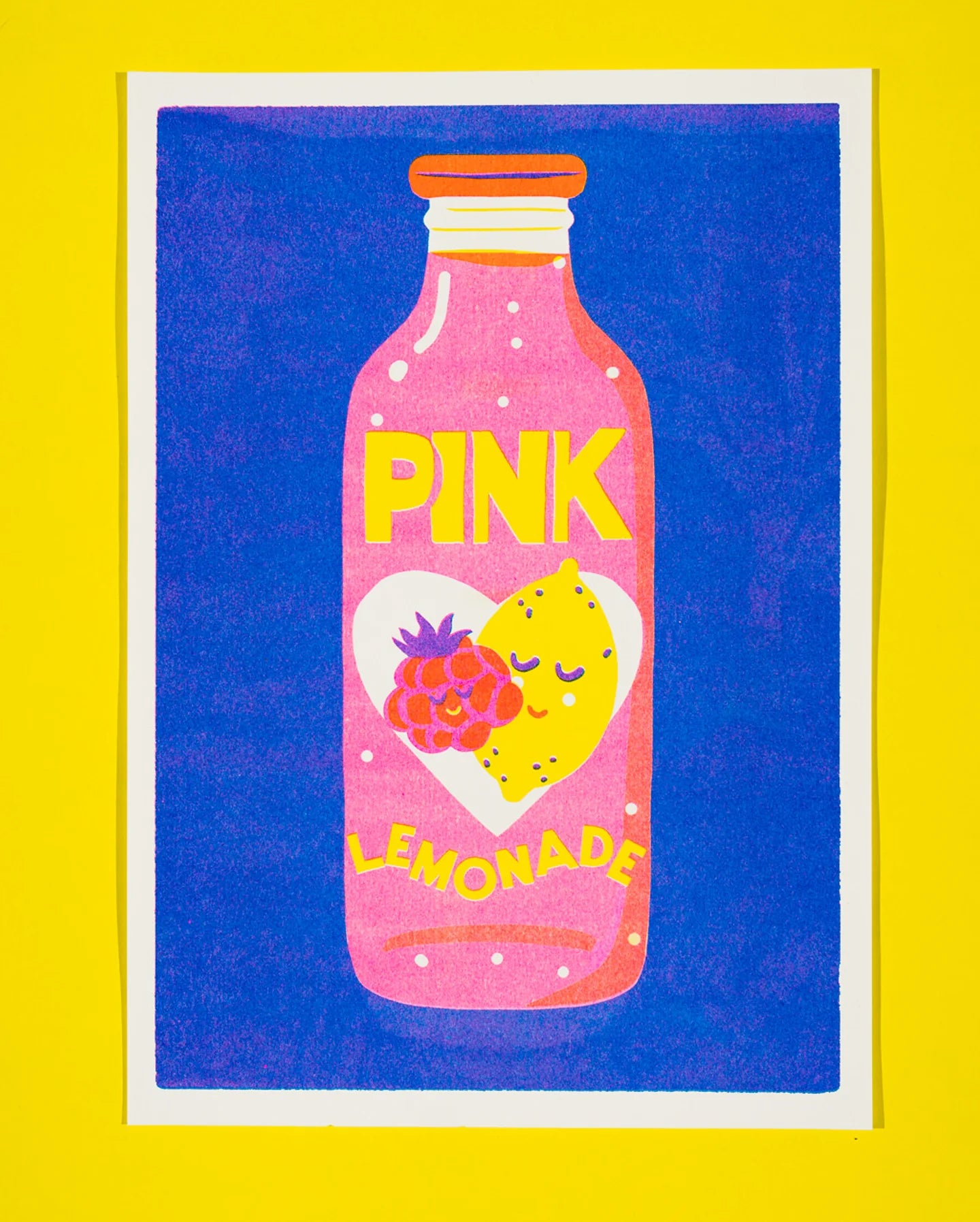 A colourful art print featuring a pink lemonade bottle with a raspberry and a yellow lemon on the label, set against a blue background with a white border and a bright yellow outer background.