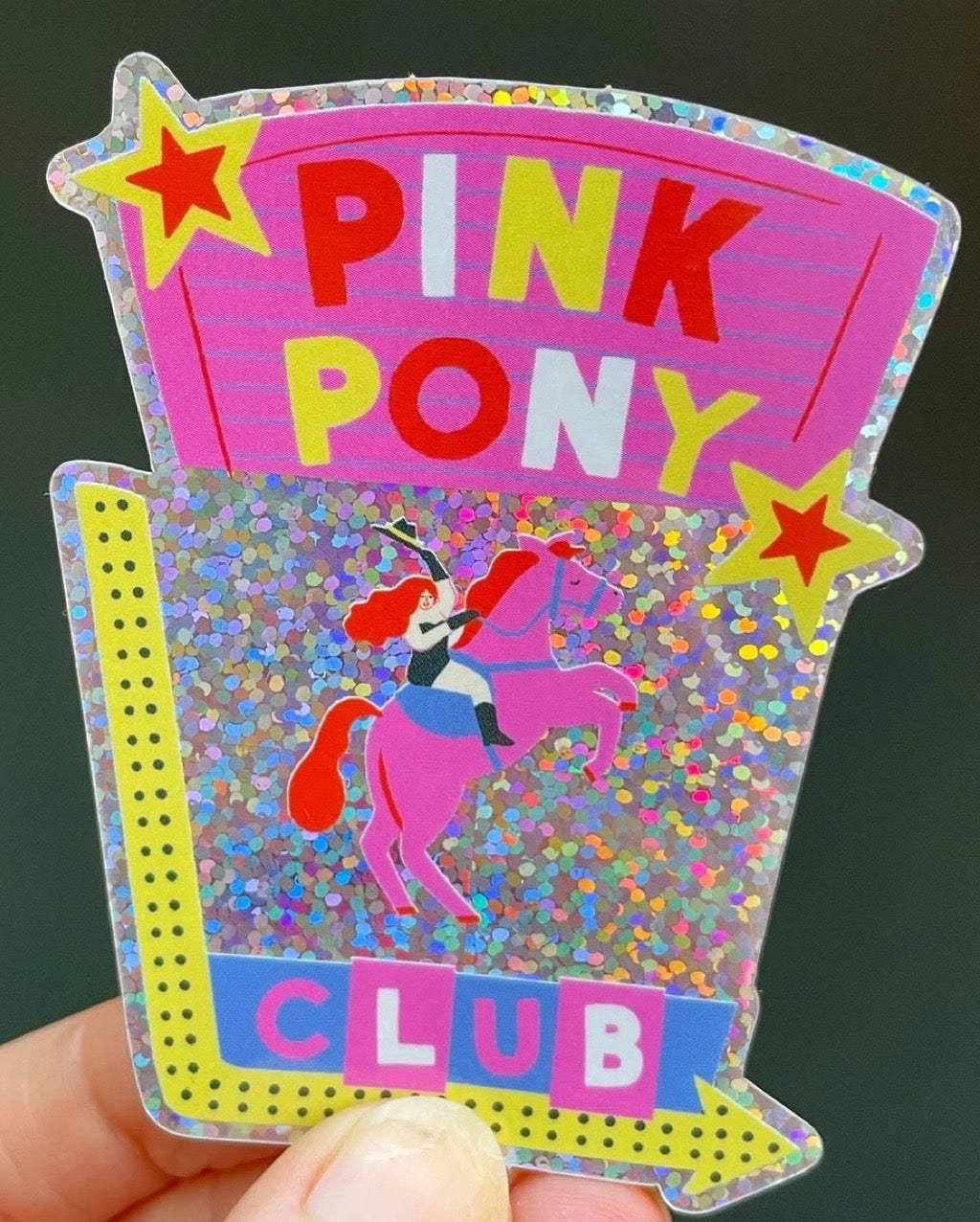 Glittery card with 'Pink Pony Club' text and a cartoon character on a dark background.