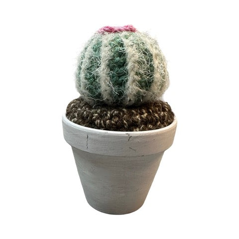 Handmade round crochet cactus with a pink flower in a white painted terracotta pot.