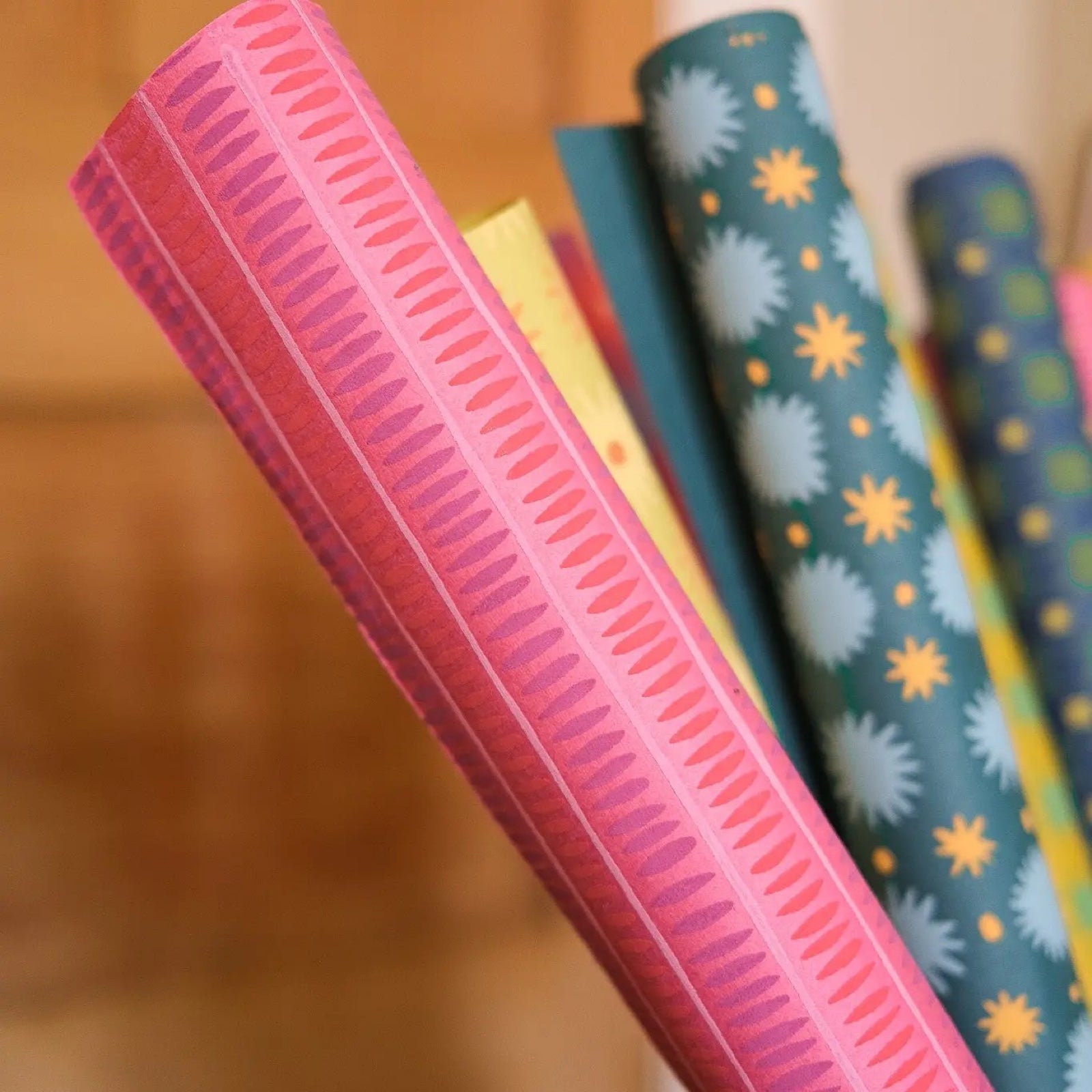 A rolled sheet of pink wrapping paper with red and purple dashed stripes.