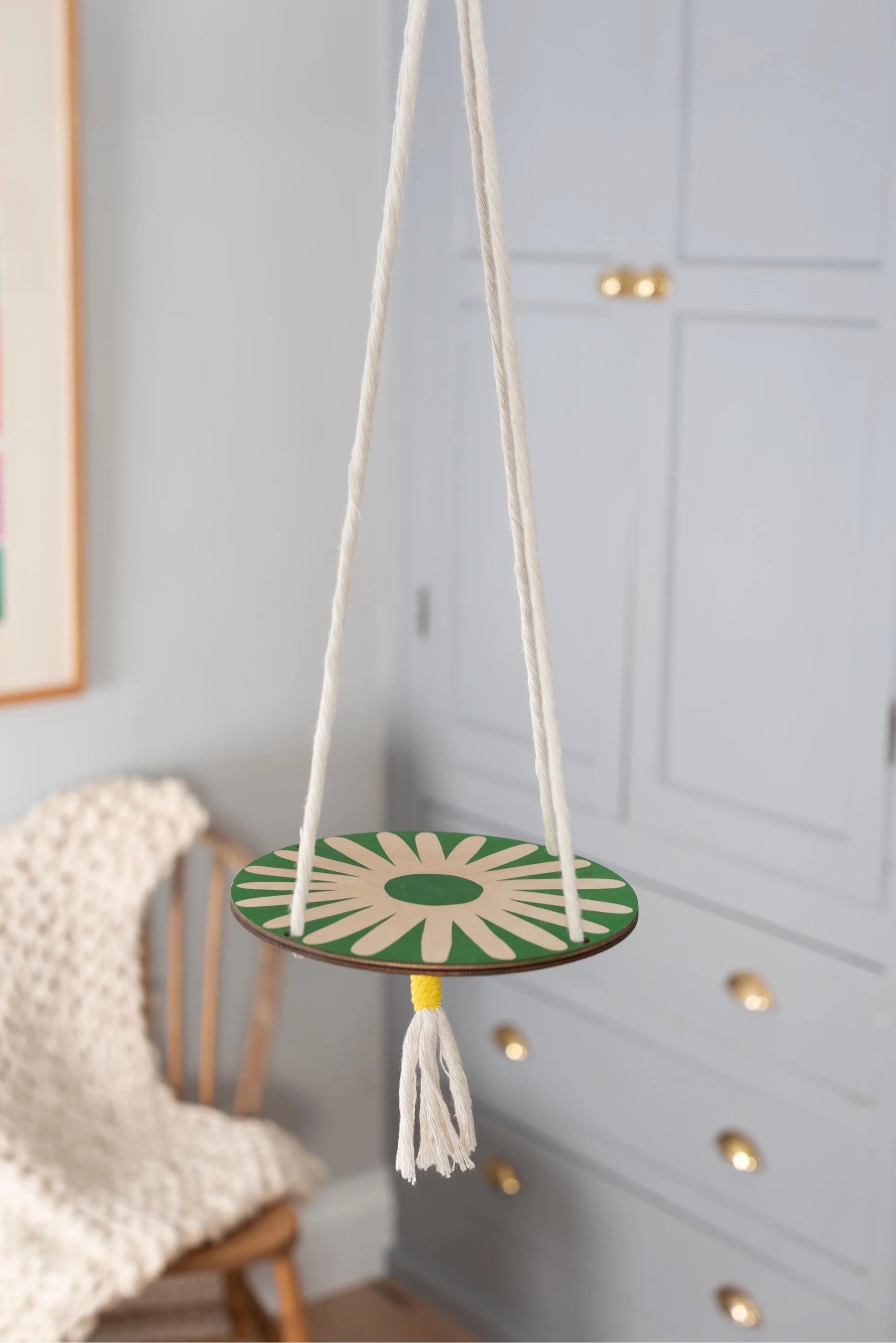 Small round hanging plant with green and white pattern hanging from a string in a room.